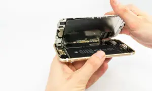 Dłonie rozkładają iPhone'a, odsłaniając baterię. Wymiana baterii iPhone 13 to proces, który można wykonać samodzielnie.