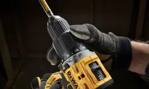 Ręka w rękawicy trzyma wkrętarkę DeWalt, gotową do pracy. Czy to najlepszy wybór, czy może lepsza byłaby Makita?