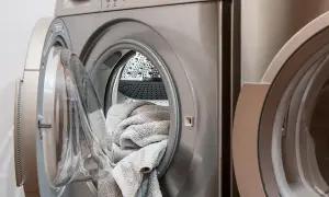 Pralka Gorenje z otwartymi drzwiczkami i szarym ręcznikiem w środku. Pojawił się błąd E07, co oznacza problem z odprowadzaniem wody.