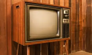 Stary telewizor z drewnianą obudową i ekranem kineskopowym. Prawdopodobnie pierwszy telewizor w domu, który gromadził całą rodzinę.