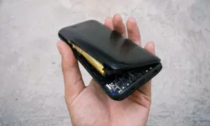 Dłoń trzyma powerbank z widoczną, spuchniętą baterią. Widać też płytkę drukowaną i porty ładowania.