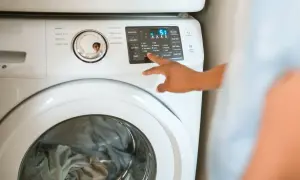 Ręka naciska przyciski na pralce Samsung, pokazując, jak zresetować pralkę Samsung.