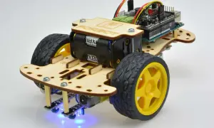 Drewniany chassis robota zasilany bateriami, z kółkami, płytką drukowaną i niebieskimi diodami LED.