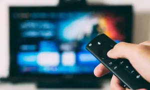 Dłoń trzyma pilot, celując w ekran telewizora. To przyszłość: telewizja naziemna bez anteny, dostępna cyfrowo.