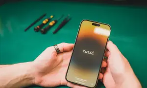Dłonie trzymające iPhone'a z napisem "cześć" na ekranie, w tle narzędzia.