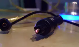 Świecący na czerwono koniec kabla optycznego, który jest częścią systemu audio. Czy to SPDIF?