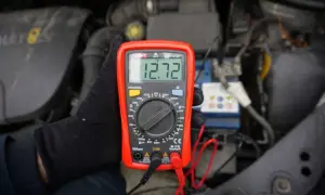 Sprawdzanie napięcia akumulatora 12V miernikiem. Wynik 12.72V.