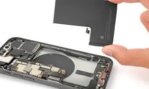 Wymiana baterii iPhone 13 Pro. Dłoń wyjmuje starą baterię z wnętrza telefonu.