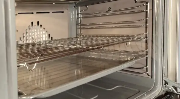 Wnętrze piekarnika z rusztami i blachą, gotowe do czyszczenia katalitycznego.