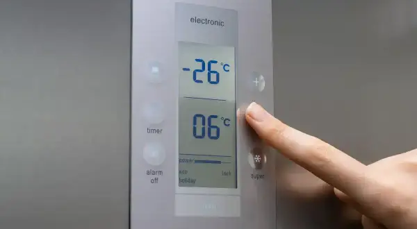 Palec naciska przycisk "super" na panelu zamrażarki. Wyświetlacz pokazuje, jaka temperatura w zamrażarce to -26°C.