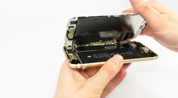 Dłonie rozkładają iPhone'a, odsłaniając baterię. Wymiana baterii iPhone 13 to proces, który można wykonać samodzielnie.