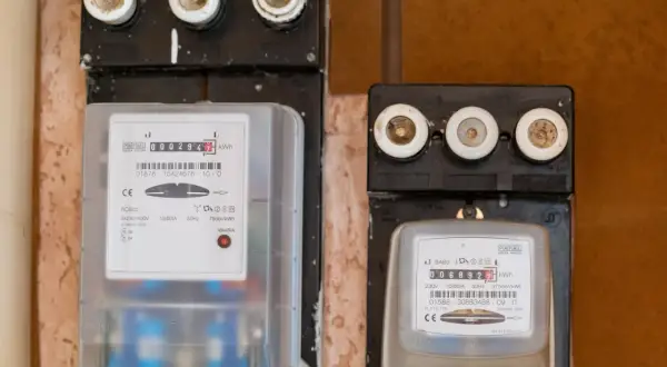 Dwa liczniki energii elektrycznej, jeden nowy, drugi starszy, gotowe do wymiany licznika Tauron.