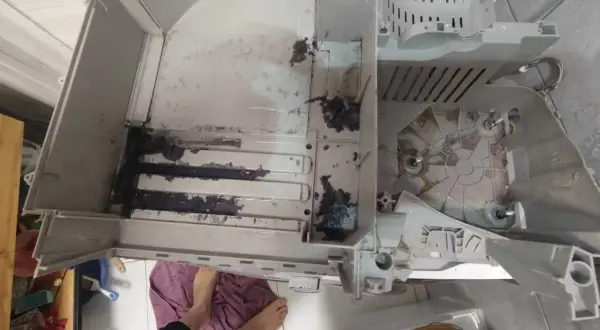 Wnętrze pralki Electrolux z błędem E20, widoczne resztki prania i brud.