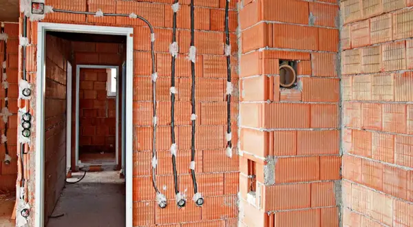 Nowe przewody elektryczne prowadzone po ścianie z pustaków ceramicznych, to nowoczesna wymiana instalacji elektrycznej bez kucia.