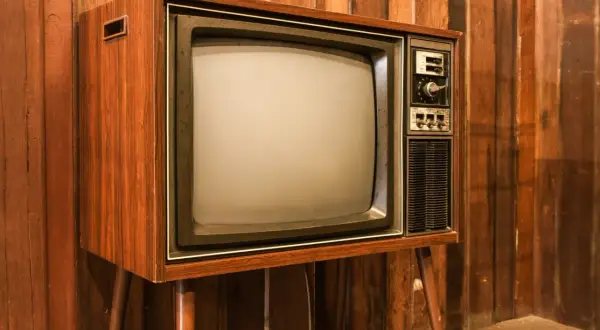 Stary telewizor z drewnianą obudową i ekranem kineskopowym. Prawdopodobnie pierwszy telewizor w domu, który gromadził całą rodzinę.