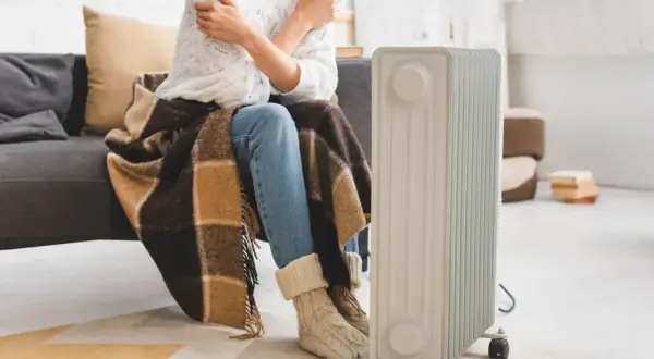 Zastanawiasz się, jaki grzejnik elektryczny do pokoju 25m2 będzie najlepszy? Ta osoba otulona kocem i w ciepłych skarpetach czeka na ciepło z nowego grzejnika.