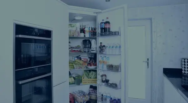Otwarta lodówka pełna jedzenia, ale niestety lodówka nie chłodzi. Widać napoje, owoce, warzywa i inne produkty spożywcze.