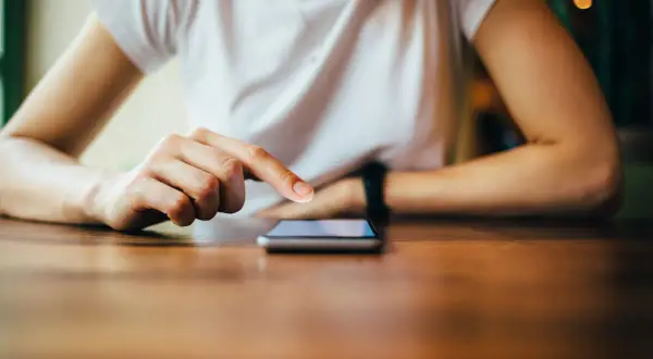 Dłoń dotyka ekranu smartfona, szukając informacji, jak zresetować telefon Redmi.