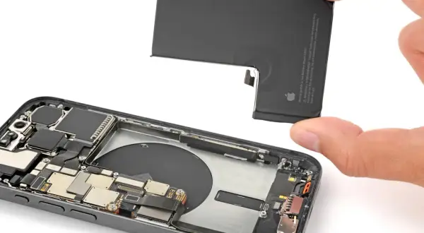 Wymiana baterii iPhone 13 Pro. Dłoń wyjmuje starą baterię z wnętrza telefonu.