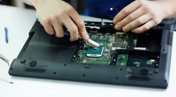 Ręce czyszczą procesor laptopa szczoteczką. Może to pomoże, gdy laptop nie chce się włączyć.