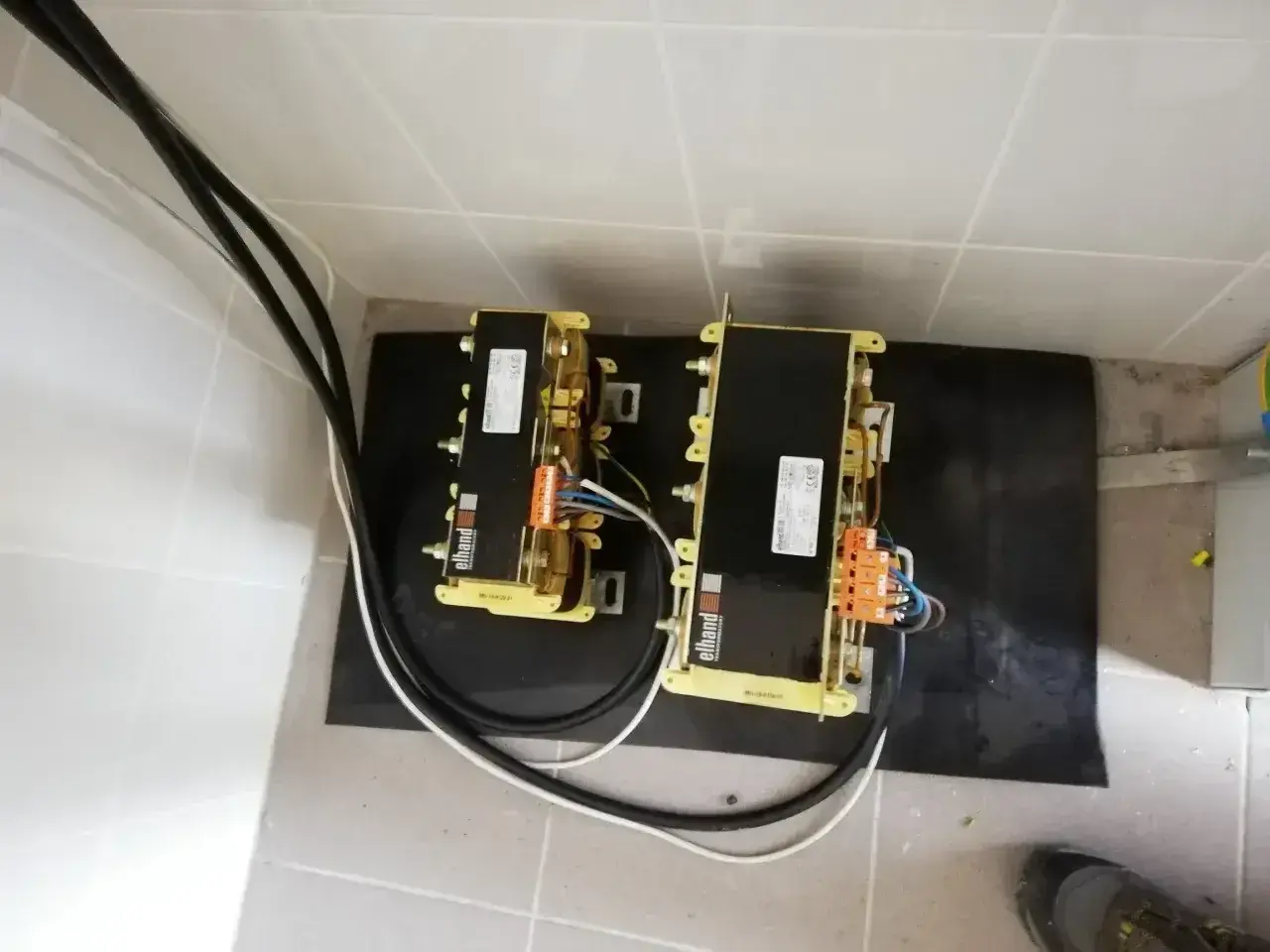 Dwa transformatory Elhand, każdy z nich to potężne urządzenie, które zarządza mocą bierną w instalacji elektrycznej.