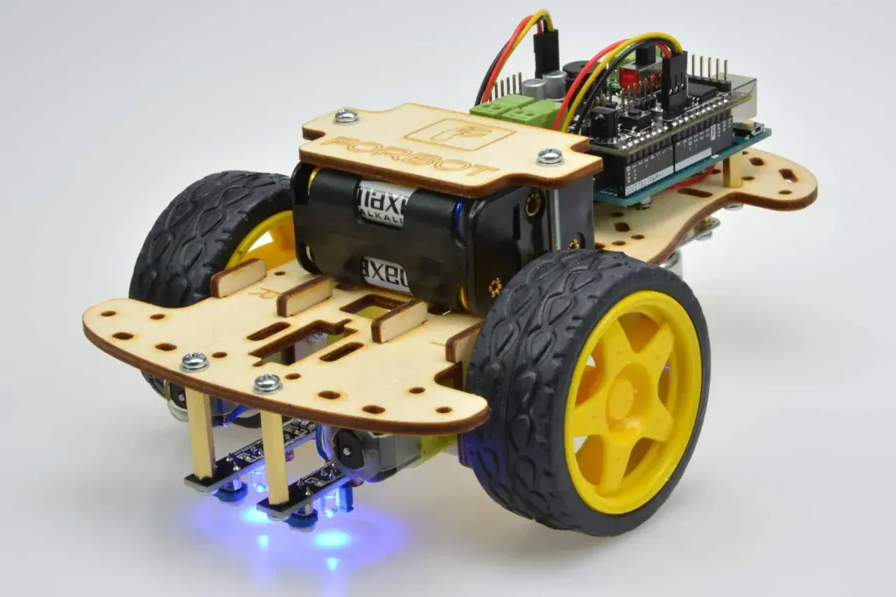 Drewniany chassis robota zasilany bateriami, z kółkami, płytką drukowaną i niebieskimi diodami LED.