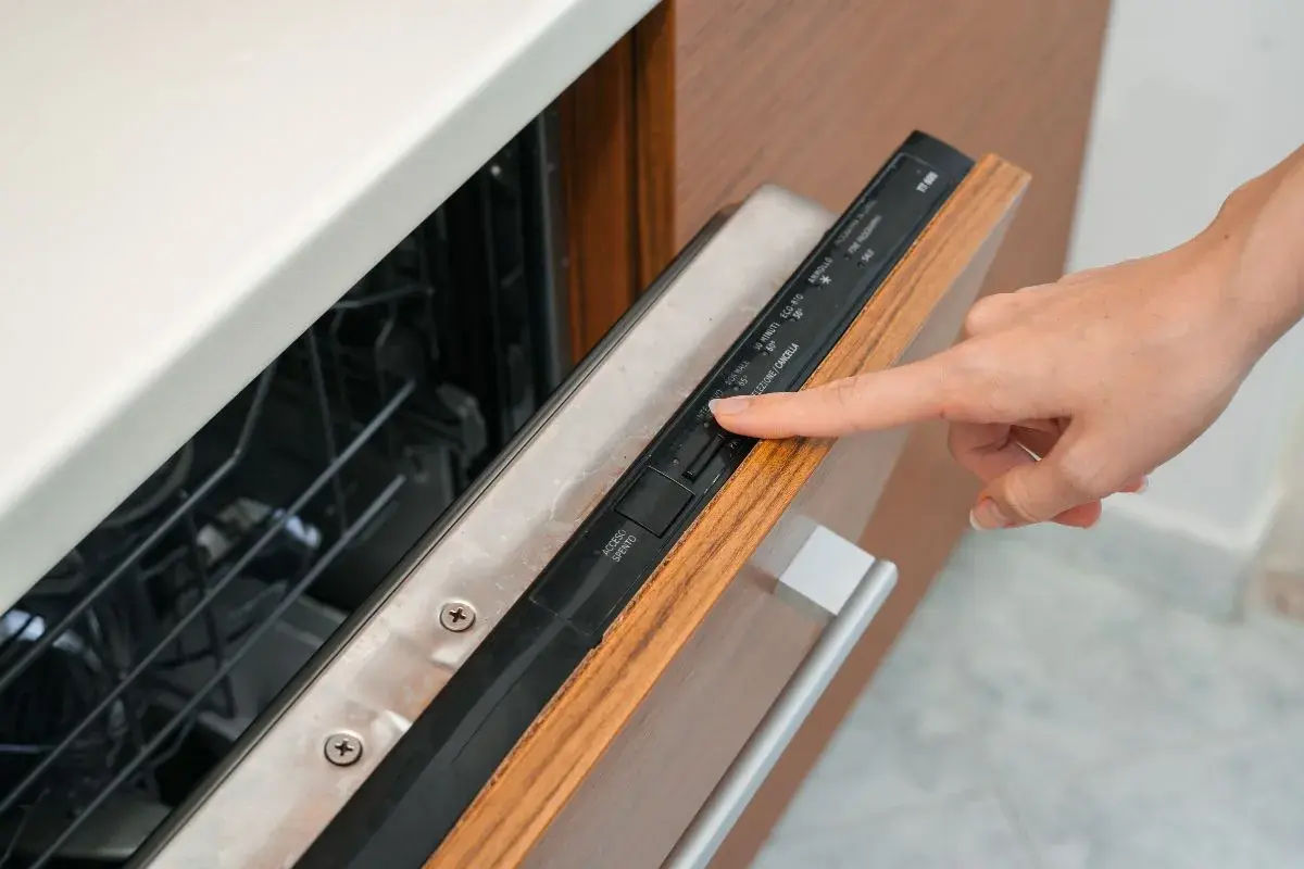 Dłoń naciska przycisk na panelu zmywarki Beko. Widoczne są symbole programów i opcji, np. "ECO-810".