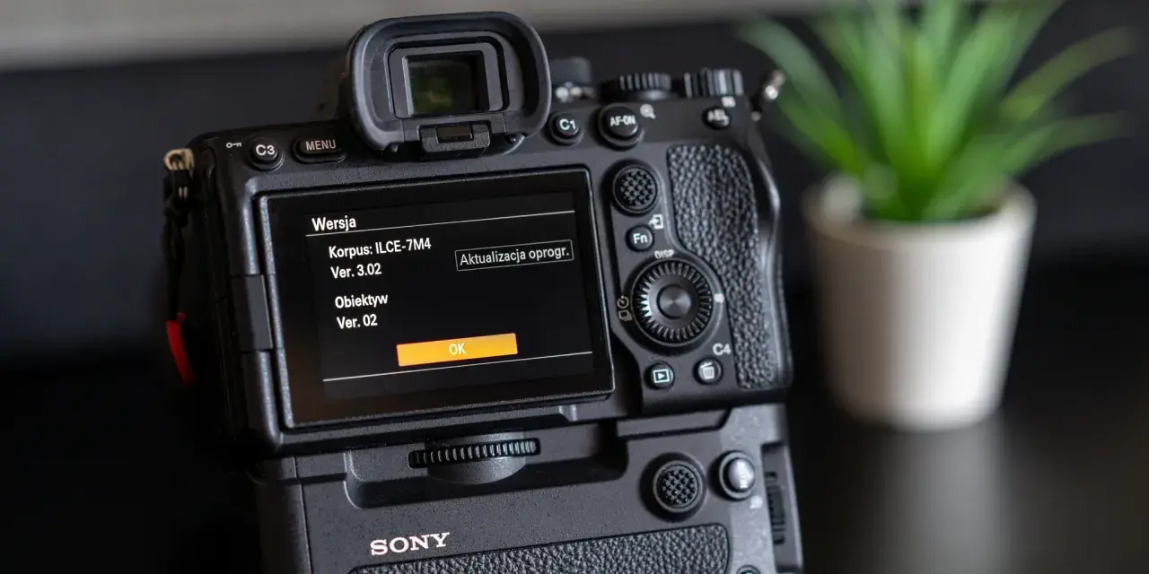 Tył aparatu Sony z ekranem pokazującym wersję oprogramowania korpusu i obiektywu.