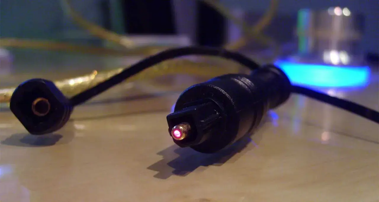 Świecący na czerwono koniec kabla optycznego, który jest częścią systemu audio. Czy to SPDIF?