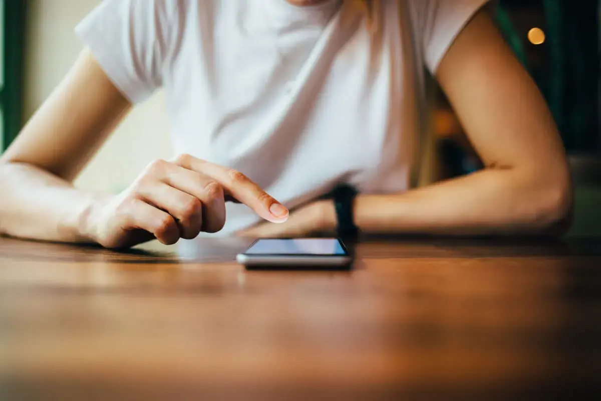Dłoń dotyka ekranu smartfona, szukając informacji, jak zresetować telefon Redmi.