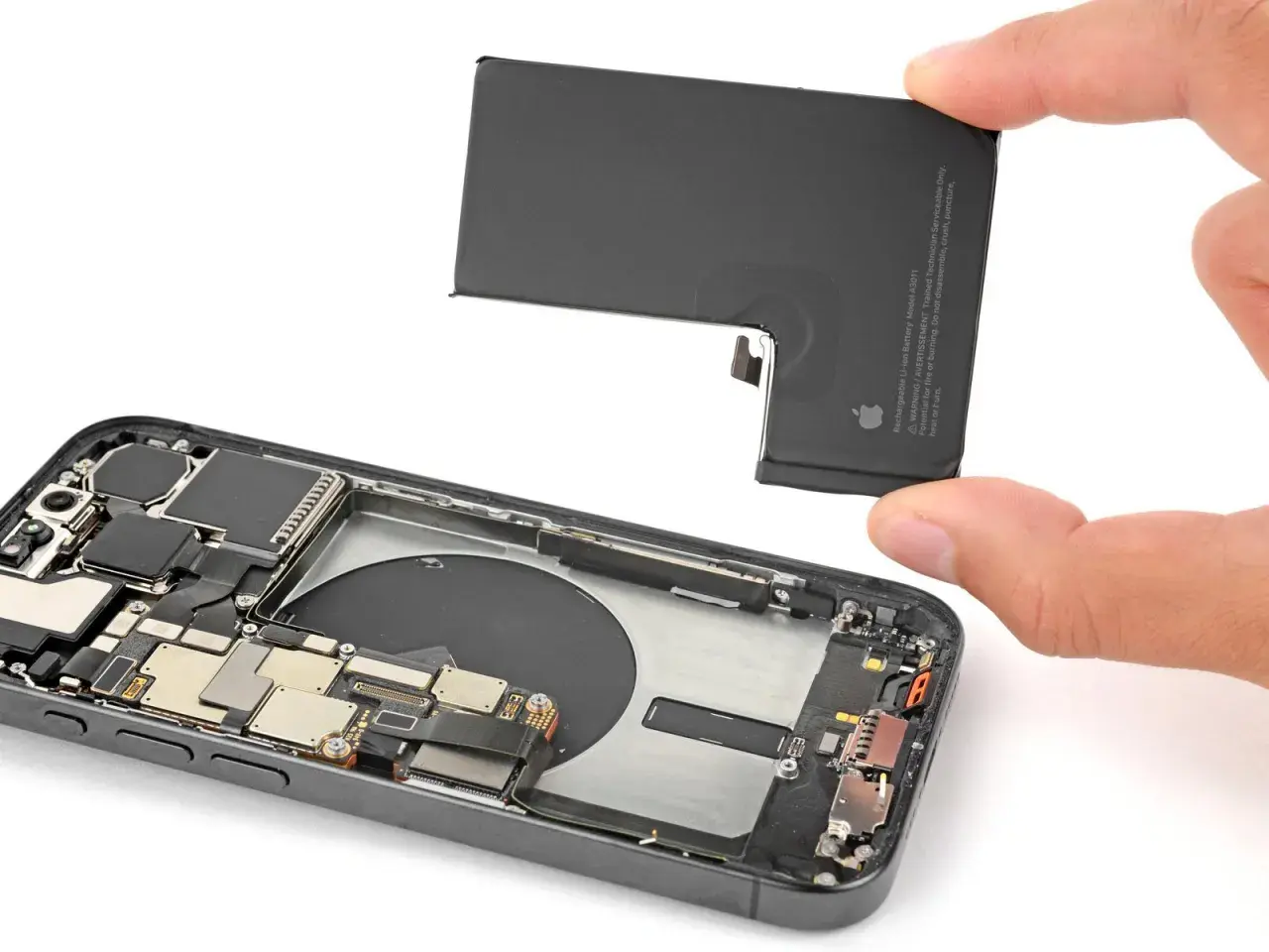Wymiana baterii iPhone 13 Pro. Dłoń wyjmuje starą baterię z wnętrza telefonu.