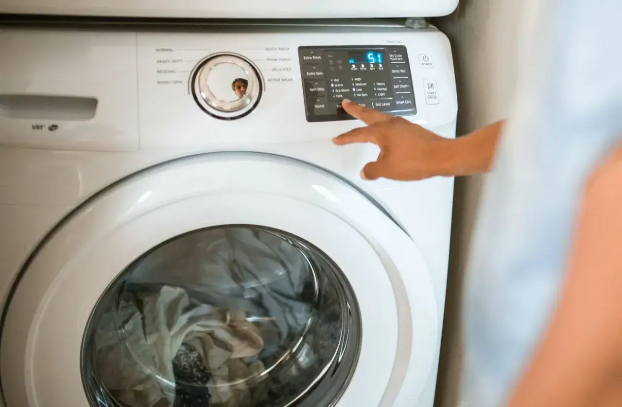Pralka Whirlpool z awaryjnym otwieraniem drzwi. Dziecko patrzy w bęben, a ręka wybiera program.
