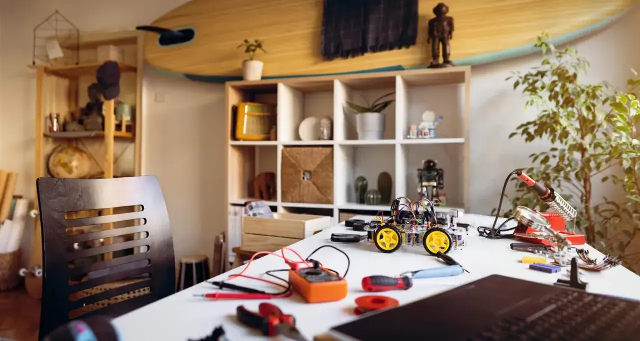 Stół do kursu elektroniki z robotem, lutownicą i miernikiem.