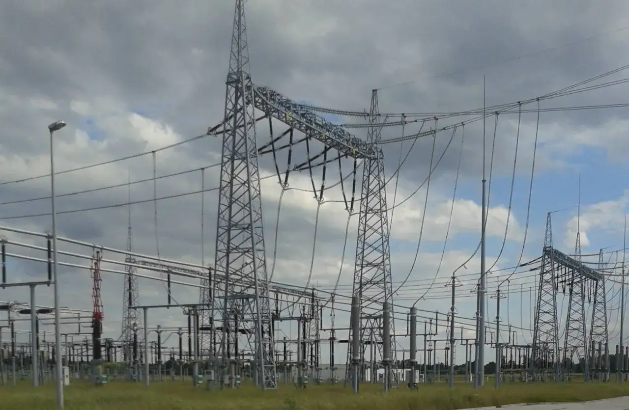 Ogromna infrastruktura energetyczna z wieżami i przewodami, gdzie panuje wysokie napięcie.