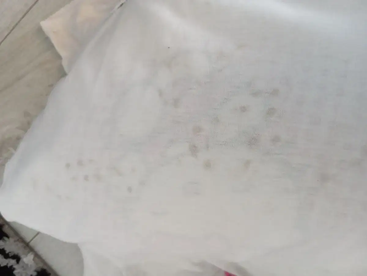 Biała koszulka poplamiona szarymi plamkami, jakby pralka brudzi ubrania na szaro.